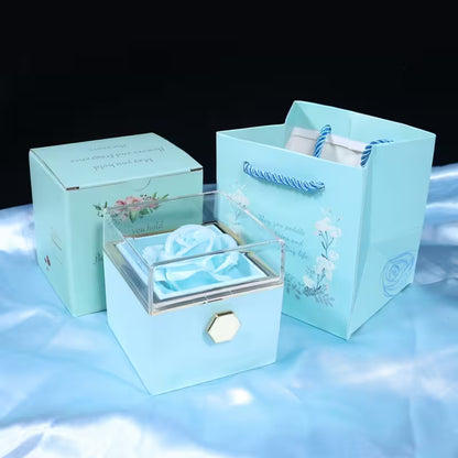 Set of light blue gift box, jewelry box, and bag with floral designs on a reflective surface.