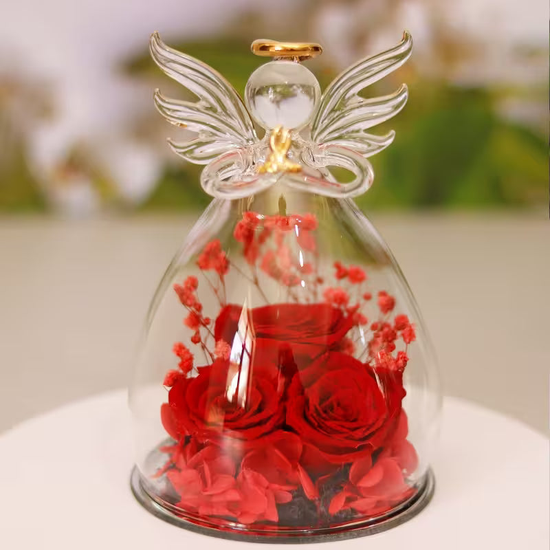 Glass angel figurine with red roses inside on a white surface