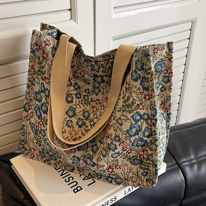 Floral patterned tote bag with beige handles on a surface.