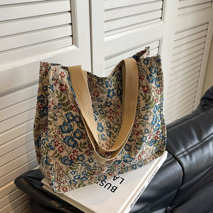 Floral patterned tote bag with beige handles on a black surface against a white shutter background