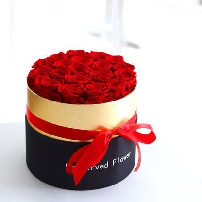 Round black box with red roses and a red ribbon on a white background