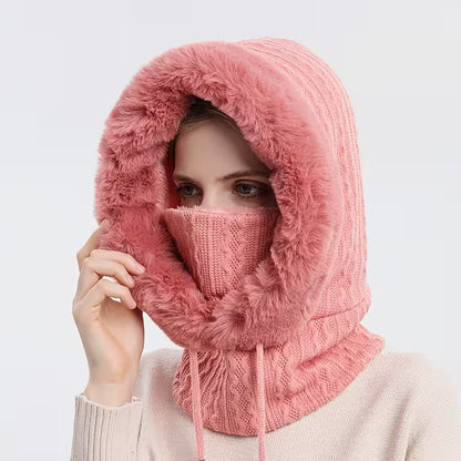 Person wearing a pink knitted hood with a fluffy texture on a light gray background