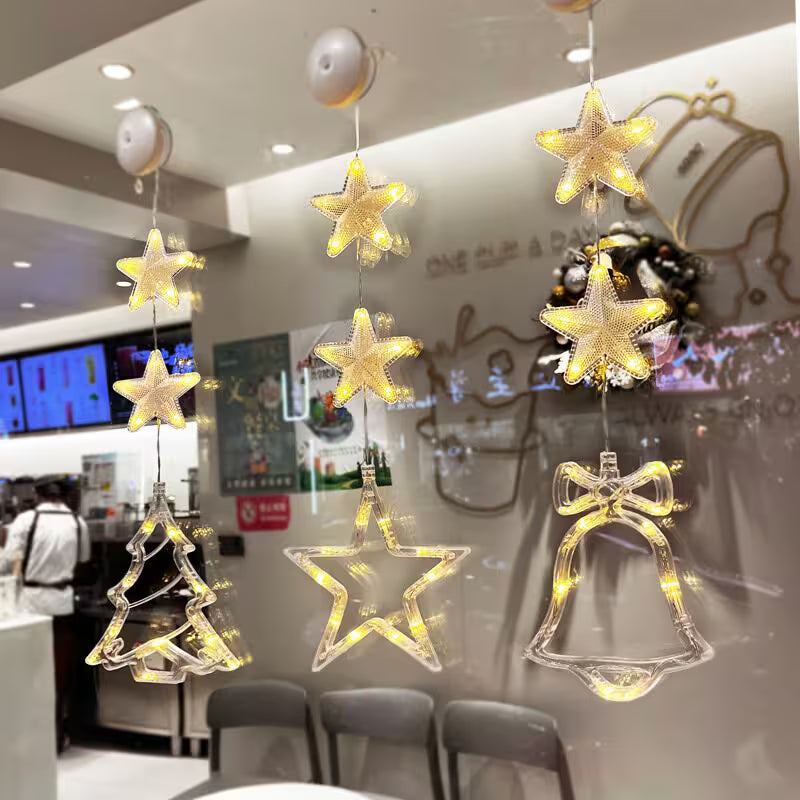 Decorative hanging lights shaped like stars, trees, and bells in a restaurant setting.