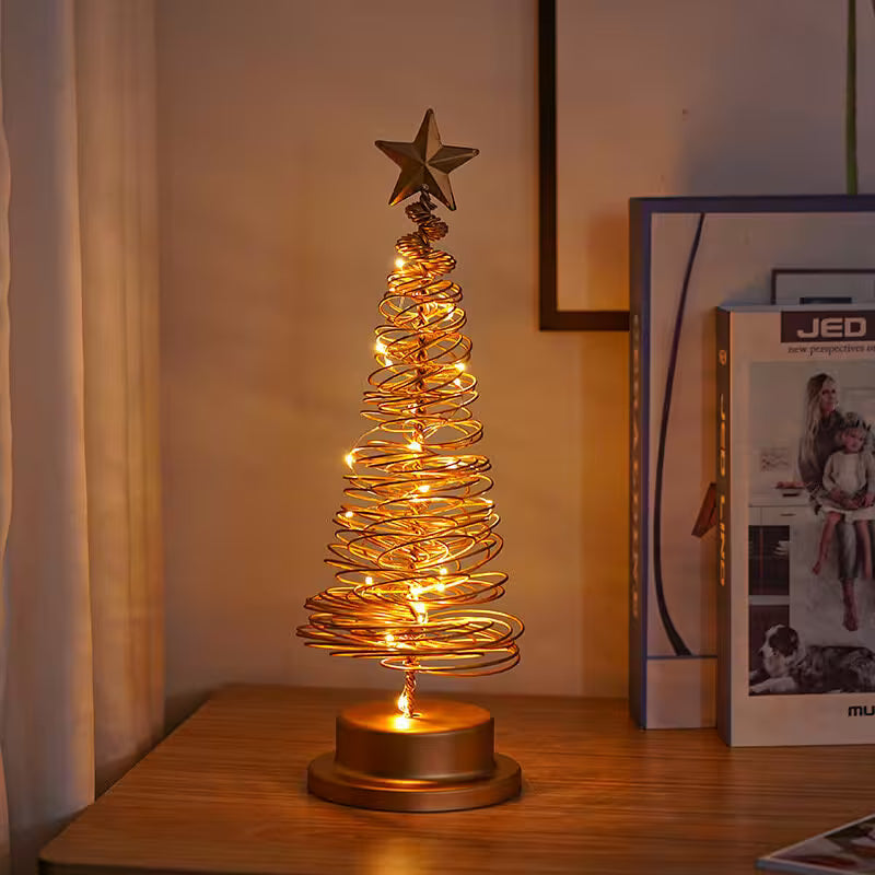 Decorative table lamp shaped like a Christmas tree with lights on a wooden surface.