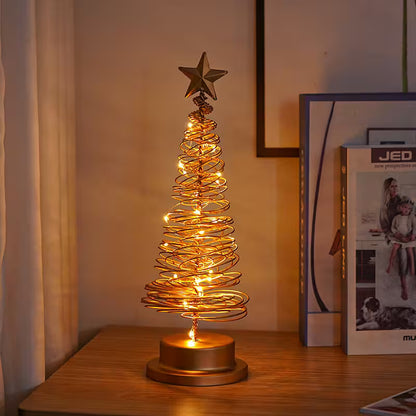 Decorative table lamp shaped like a Christmas tree with lights on a wooden surface.