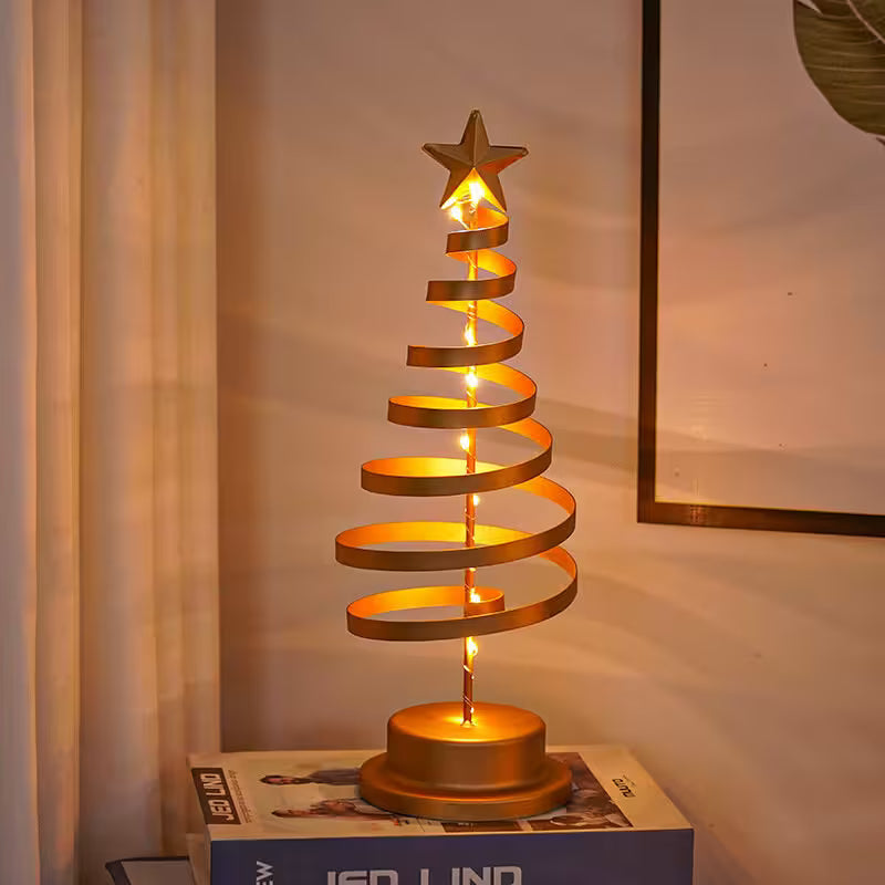 Gold spiral Christmas tree lamp on a box with a neutral background