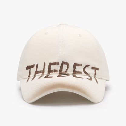 Beige cap with 'THE BEST' text on a white background