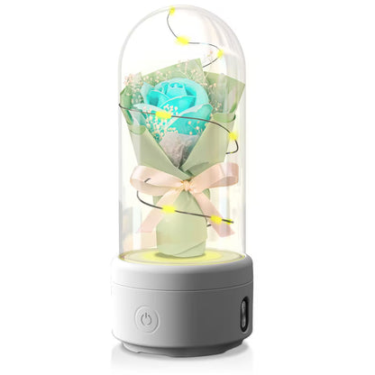 Decorative lamp with a turquoise rose inside a glass dome on a white background