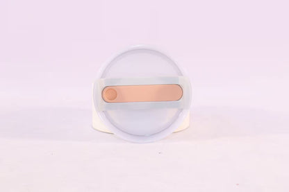 Round white object with a gold bar on a light purple background