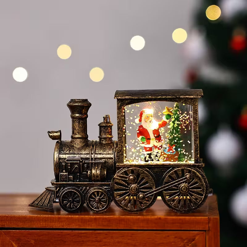 Decorative train with a Santa Claus figure inside a glass box on a wooden surface.