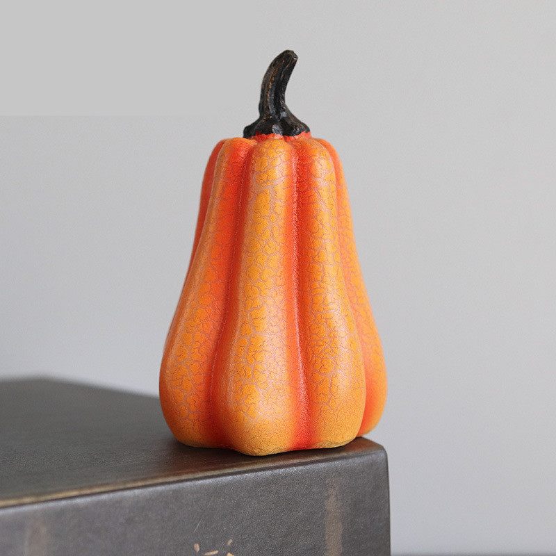 Decorative orange gourd on a gray surface with a neutral background