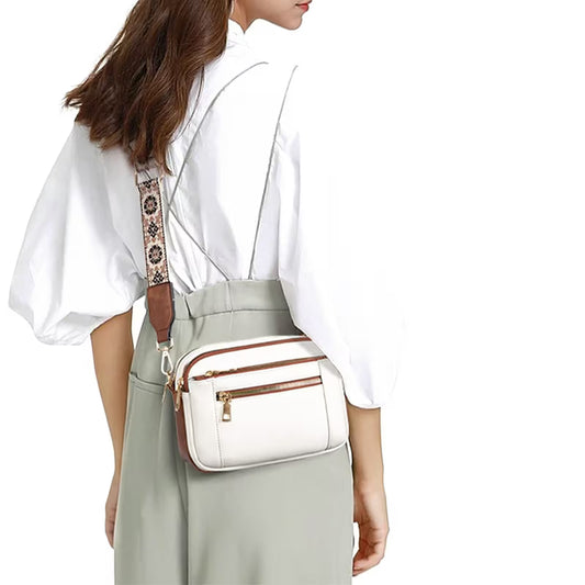 Woman wearing a white blouse and light gray pants with a white crossbody bag on a white background