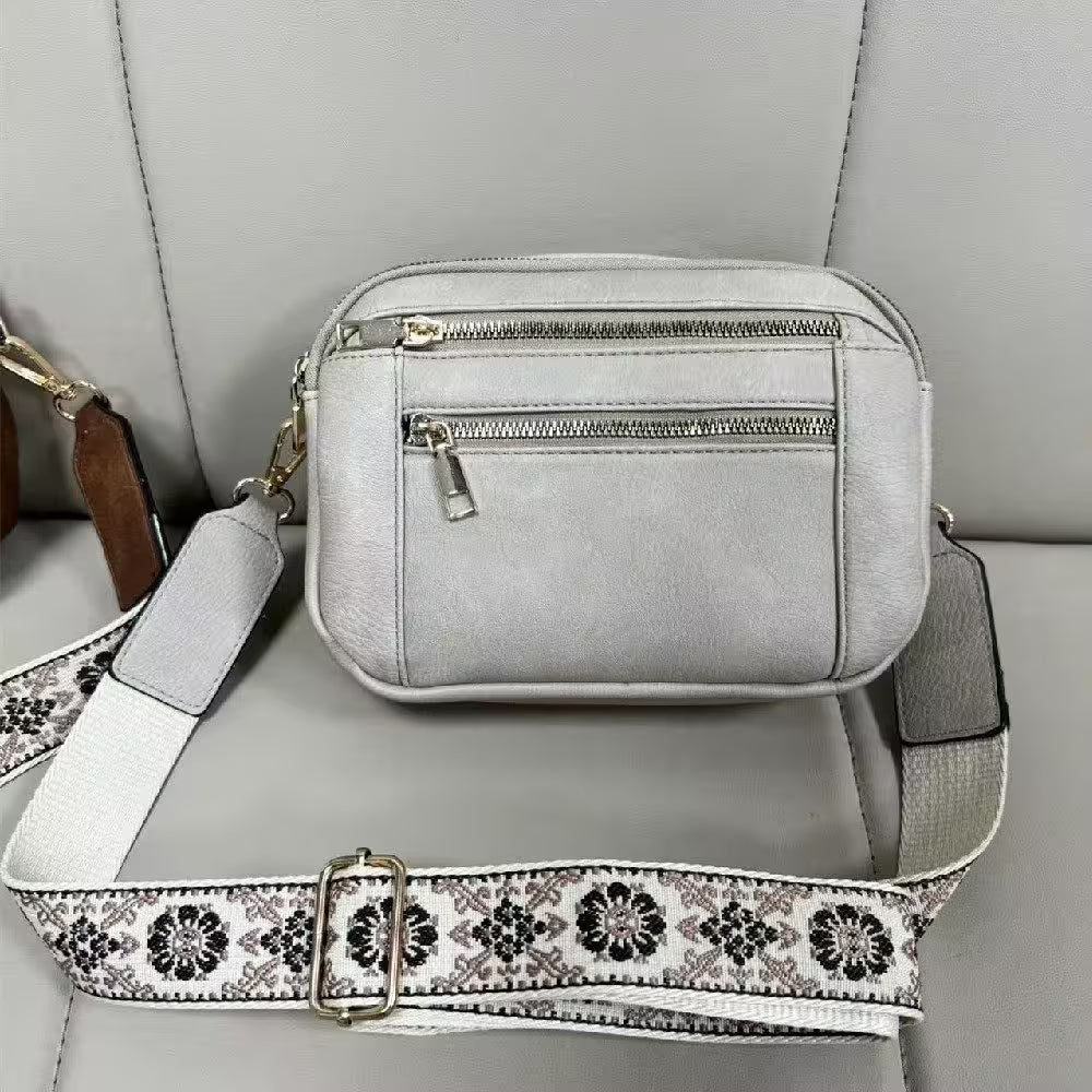 Gray handbag with a floral strap on a gray surface