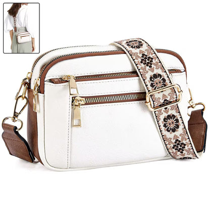 White handbag with floral strap and gold zippers on a white background