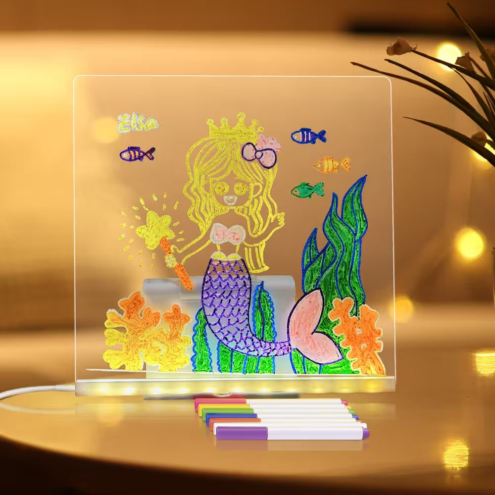 Colorful mermaid drawing on a transparent board with LED lights, placed on a reflective surface.