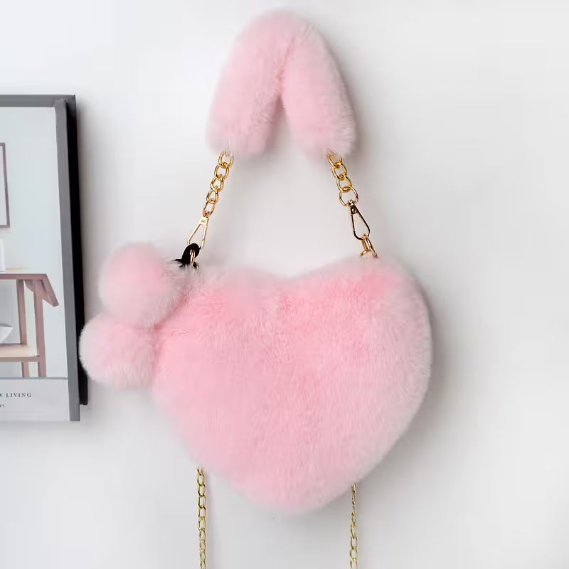 Pink heart-shaped fluffy bag with gold chain on a light gray background