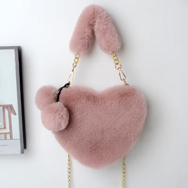 Pink fluffy heart-shaped bag with chain strap on a white background