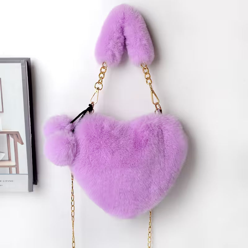 Purple heart-shaped bag with fur texture and gold chain on a white background