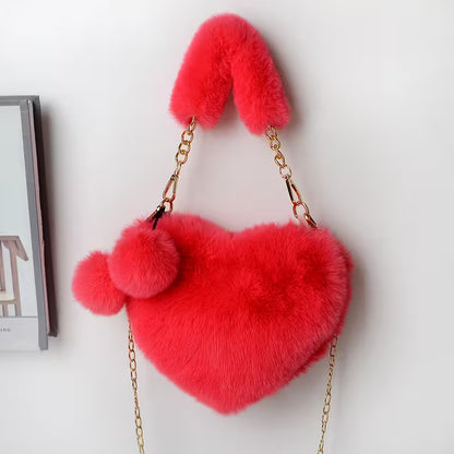 Red heart-shaped fluffy bag with pom-pom details on a white background