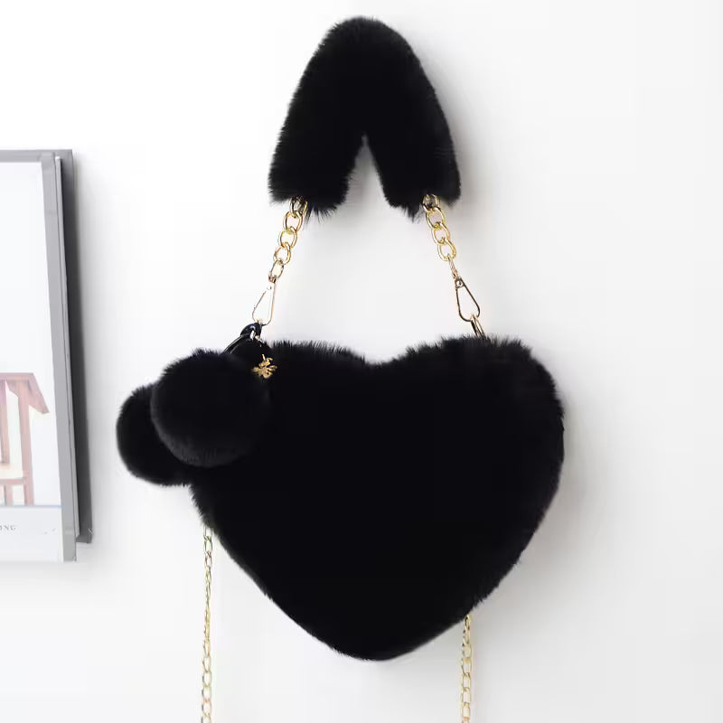 Black heart-shaped bag with fur accents on a white background