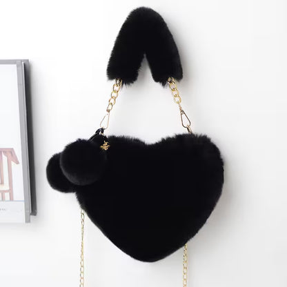 Black heart-shaped bag with fur accents on a white background
