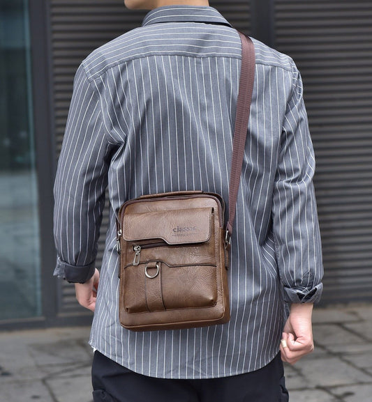 Person wearing a brown leather crossbody bag with a striped shirt against a neutral background