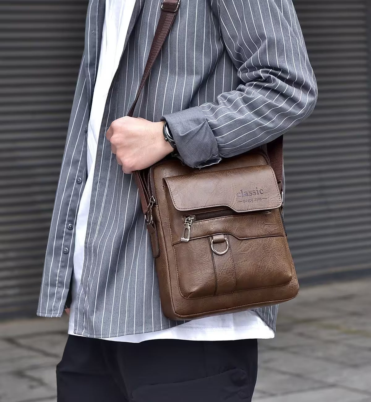 Person wearing a brown leather bag with 'classic' branding against a neutral background