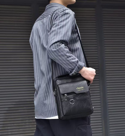 Person holding a black leather bag with 'classic' branding against a gray background
