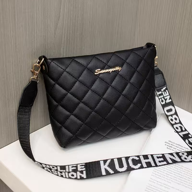 Black quilted handbag with a branded strap on a wooden surface