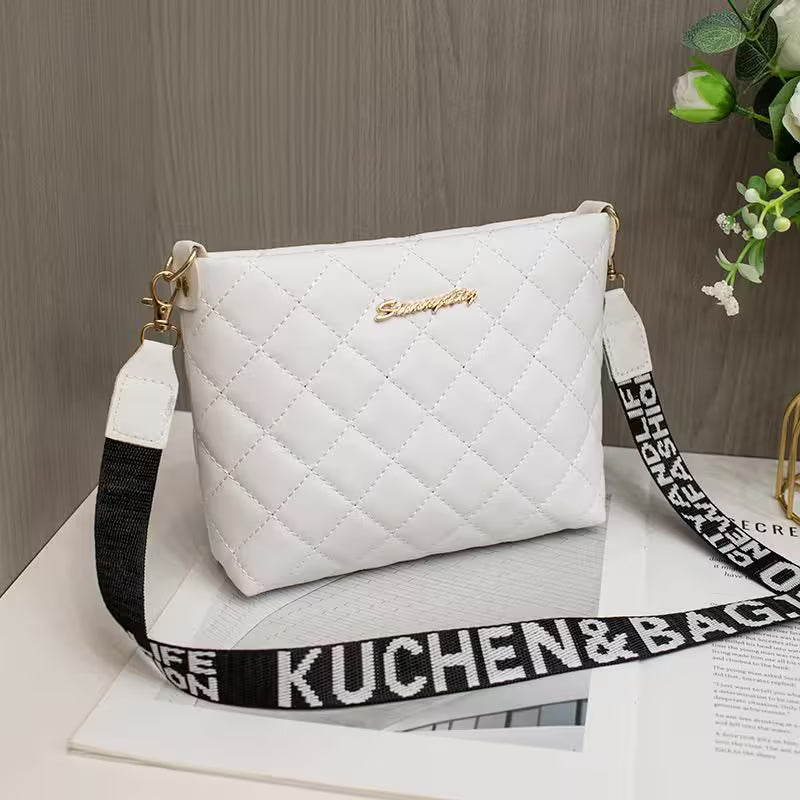White quilted handbag with a black and white strap on a wooden surface