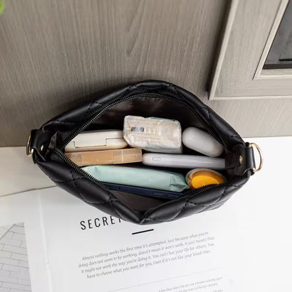 Black quilted handbag with electronic devices on a surface