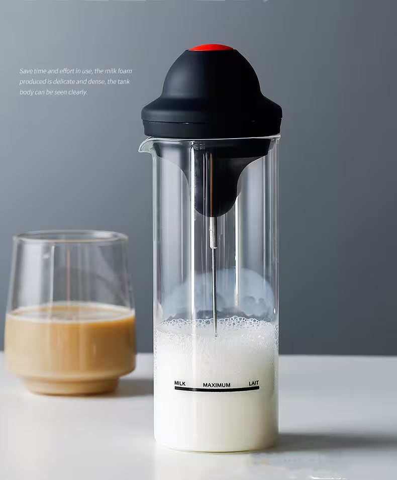 Milk frother with a glass of frothed milk on a gray background