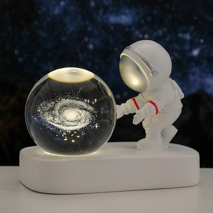 Spaceman figurine interacting with a galaxy model on a dark background