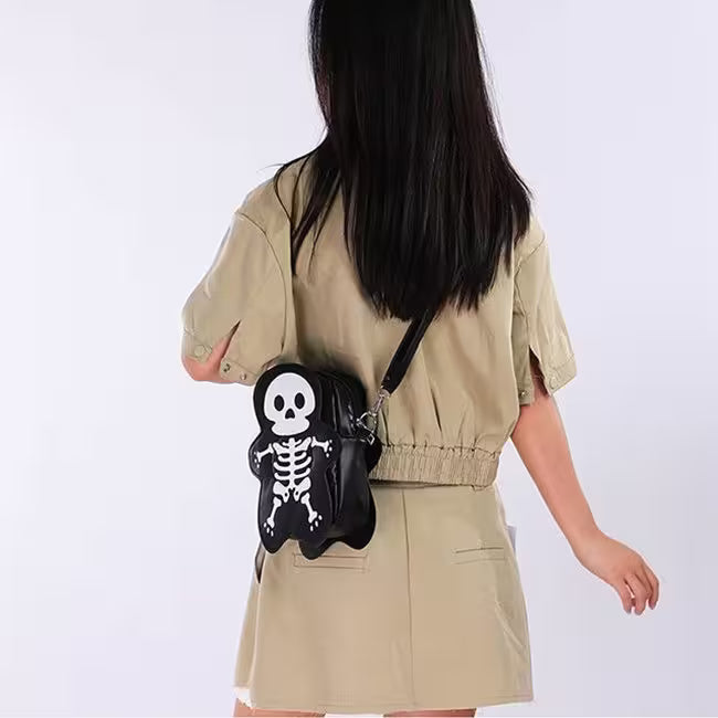Person wearing a beige outfit with a black skeleton-themed bag on a white background