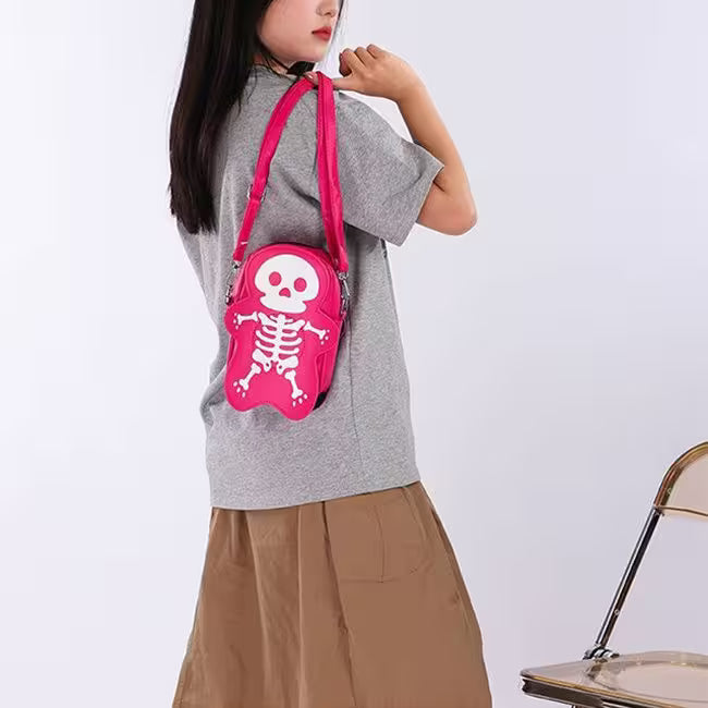 Person wearing a gray shirt and brown pants with a pink skeleton bag on a white background