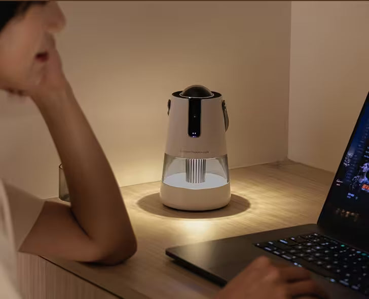 Person using a laptop with a modern lamp on a desk