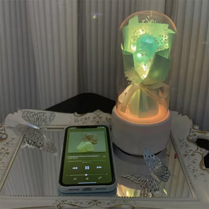 Decorative lamp with green light on a table next to a smartphone displaying a music app.