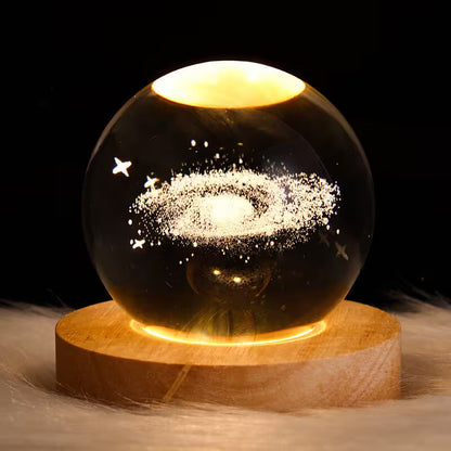 Glass sphere with starry design on a wooden base against a dark background