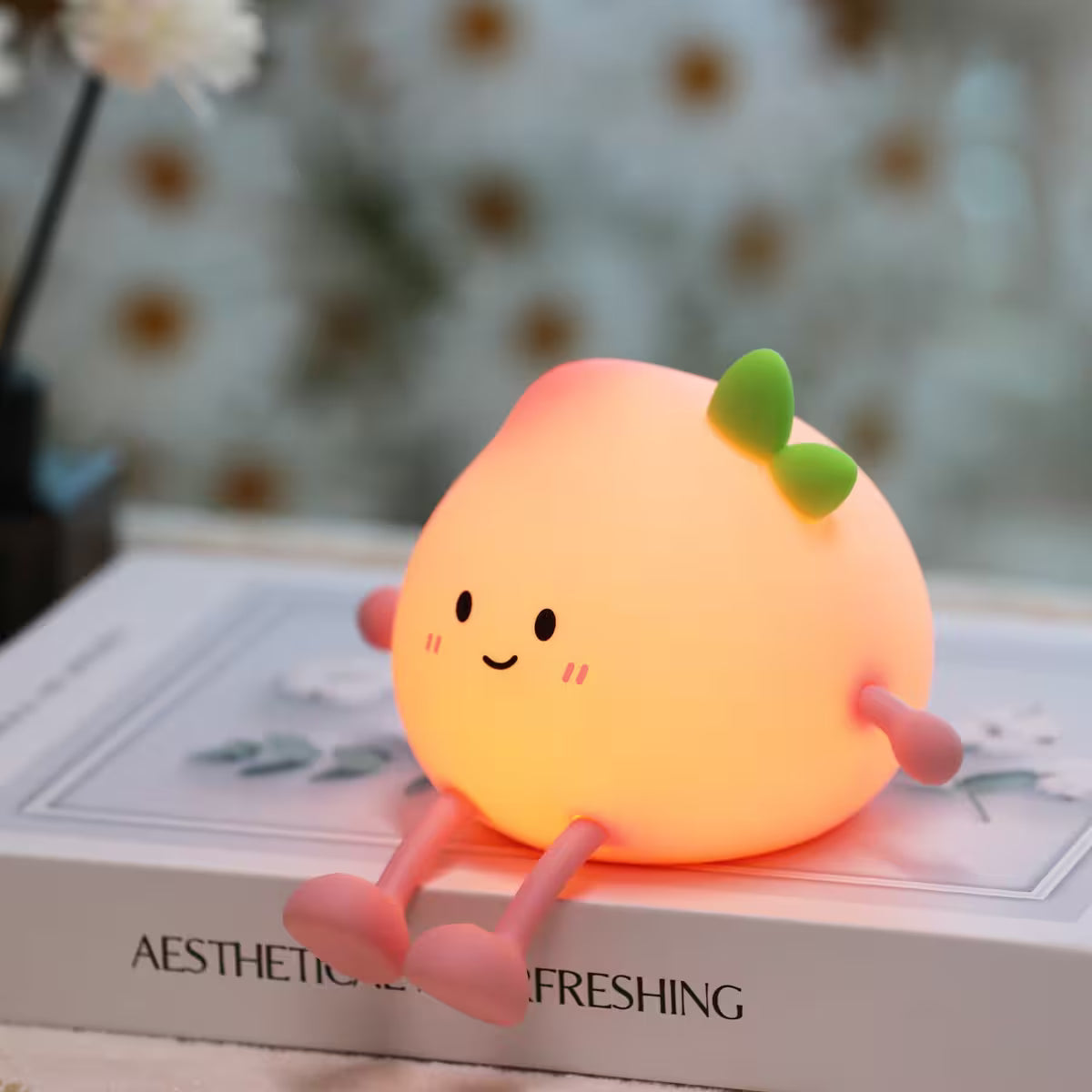 Cute, glowing peach-shaped night light on a book with a blurred background