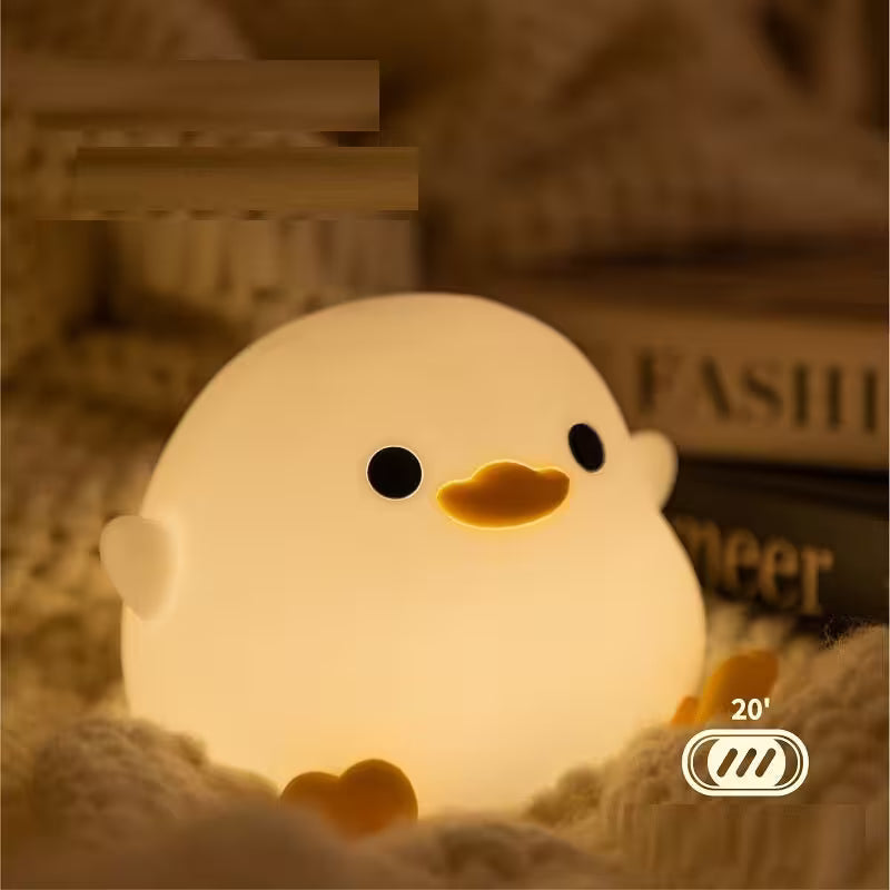 Cute chick-shaped night light with a warm glow on a soft surface.