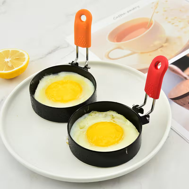 Two egg frying pans with eggs on a white plate, surrounded by a lemon and a magazine.