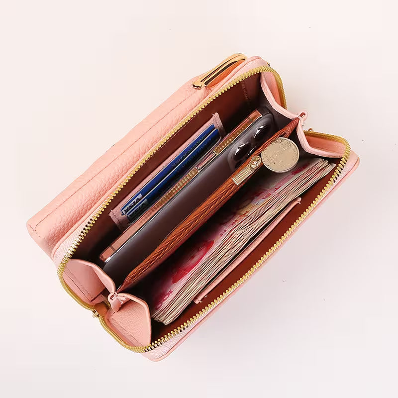 Open pink wallet with various items on a light beige background