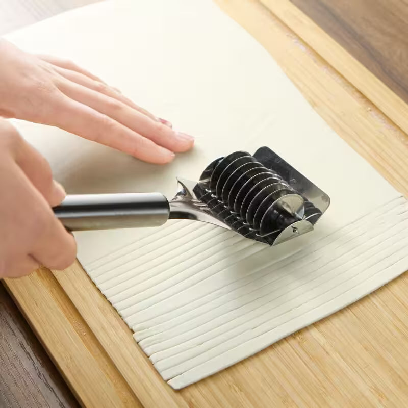 Hand using a kitchen tool on a cutting board with a wooden surface.