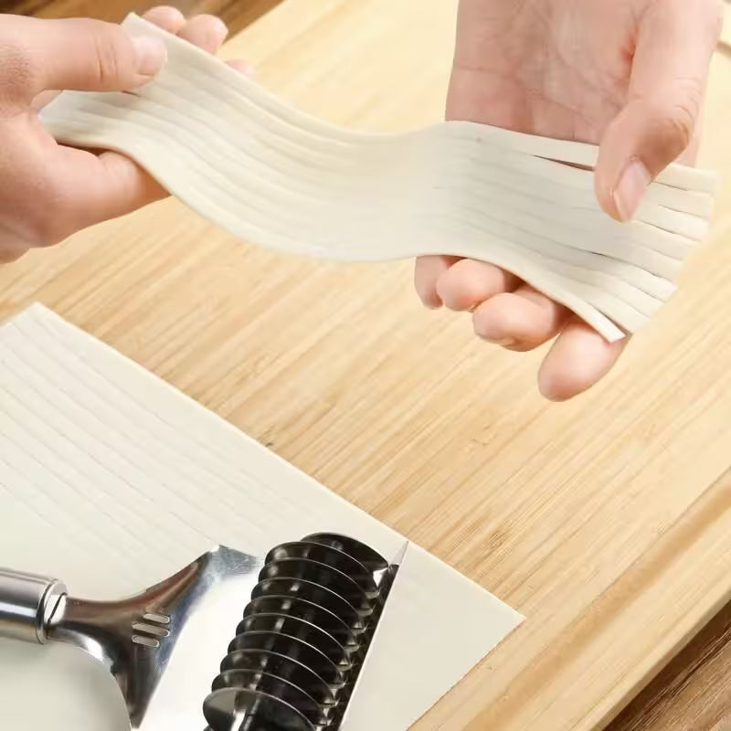 Hands stretching fresh pasta sheets with a pasta maker on a wooden surface