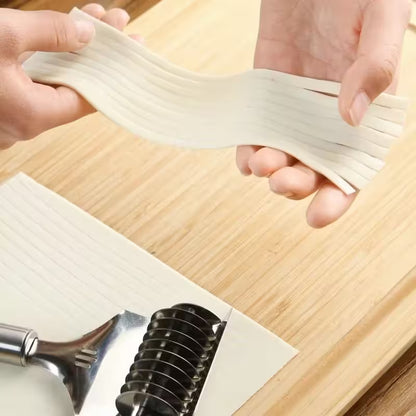 Hands stretching fresh pasta sheets with a pasta maker on a wooden surface
