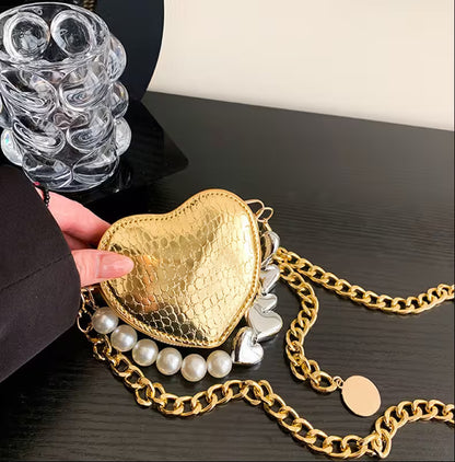 Gold heart-shaped handbag with chain strap on a dark surface