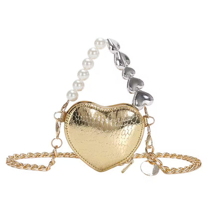 Heart-shaped gold bag with a pearl and silver chain on a white background