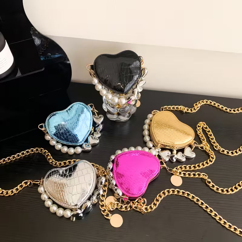 Heart-shaped jewelry cases with chains on a dark surface