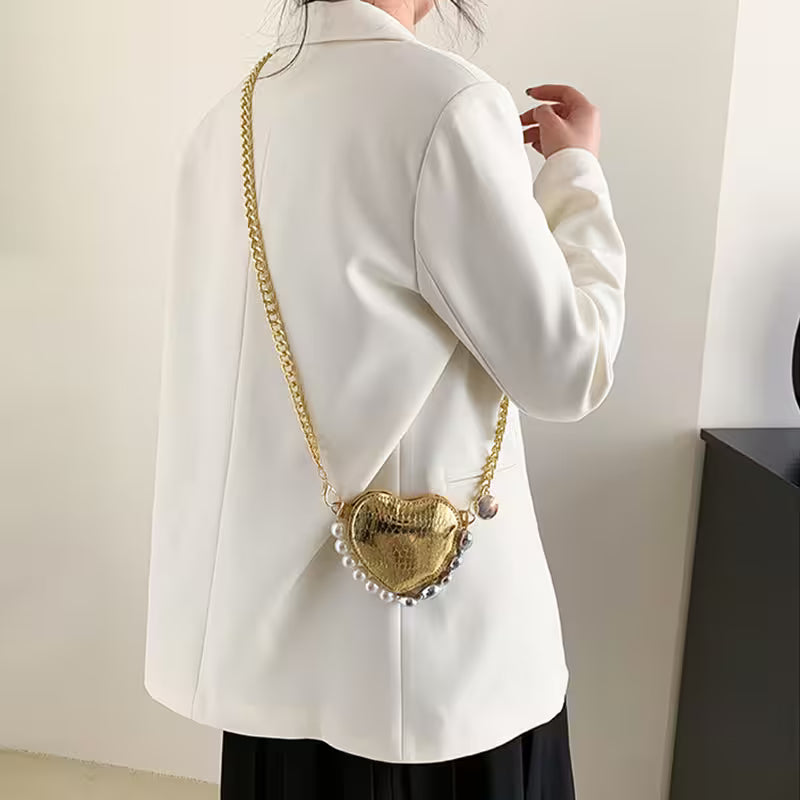 Person wearing a white coat with a gold heart-shaped bag over their shoulder.