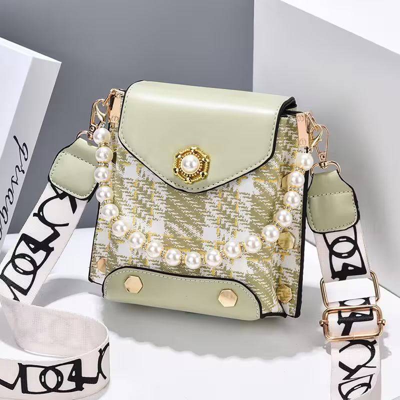 Green handbag with pearl embellishments on a white background
